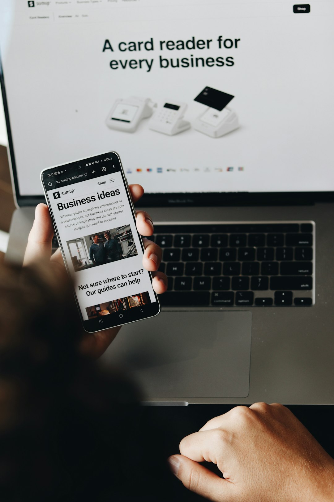 brand-01 A person is holding a smartphone displaying a page on business ideas. This image emphasizes the support SumUp provides to entrepreneurs and small business owners, helping them grow and manage their payment processes seamlessly.